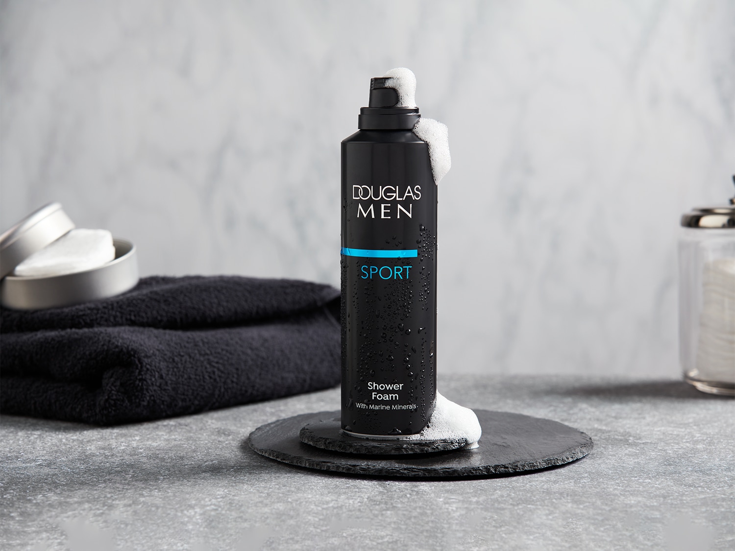 Le flacon noir de mousse de douche Douglas Men Sport, agrémenté d'une touche de bleu, promet une expérience rafraîchissante avec des minéraux marins.