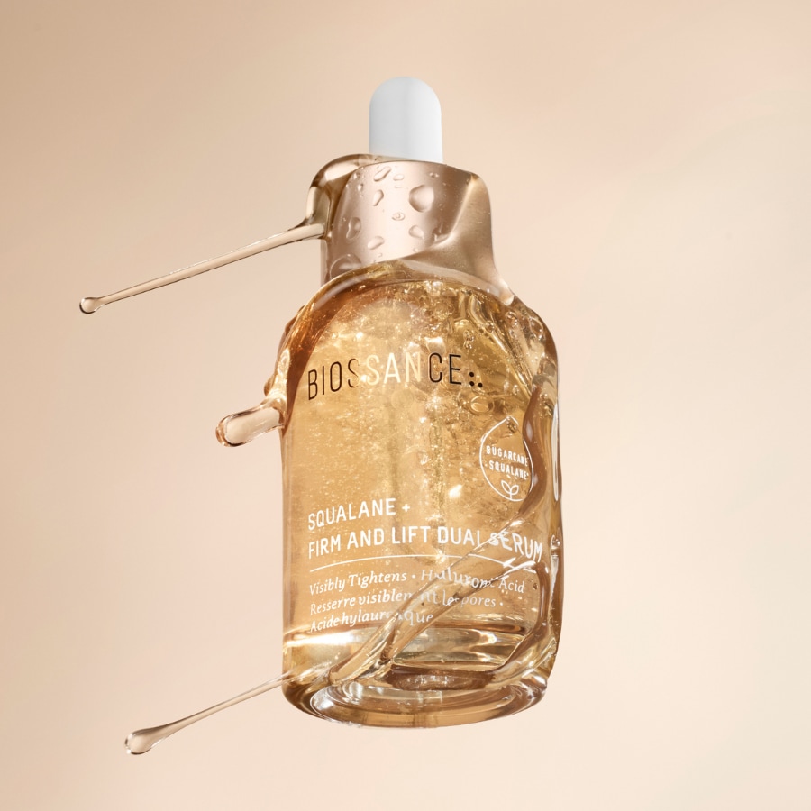 Nahaufnahme von Biossance Squalane + Firm and Lift Dual Serum in einer durchsichtigen Flasche mit Pipette, die straffende und feuchtigkeitsspendende Wirkung verspricht.