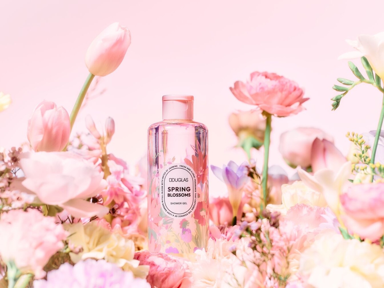 Découvrez le gel douche Spring Blossoms de Douglas, un parfum floral frais et léger, présenté dans un flacon transparent orné de motifs floraux, entouré de tulipes et de fleurs roses.