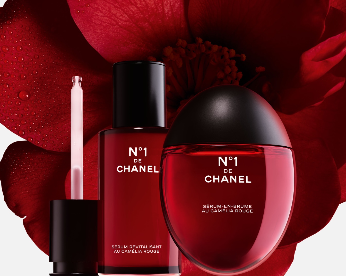 Twee rode Chanel N°1 producten, een serum in een fles met een pipet en een serum-in-mist in een ronde fles, staan voor een rode cameliabloem.