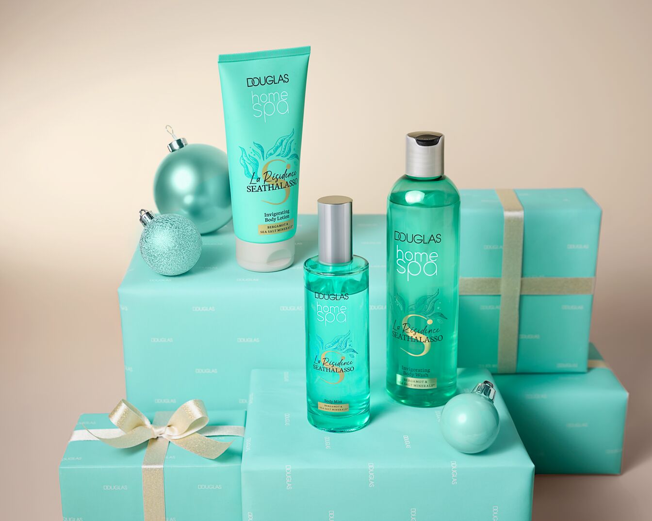 Douglas Home Spa Kollektion mit La Résidence SEATHALASSO, inklusive Body Lotion, Körperspray und Duschgel, präsentiert auf Geschenkboxen mit Schleife und Kugeln.