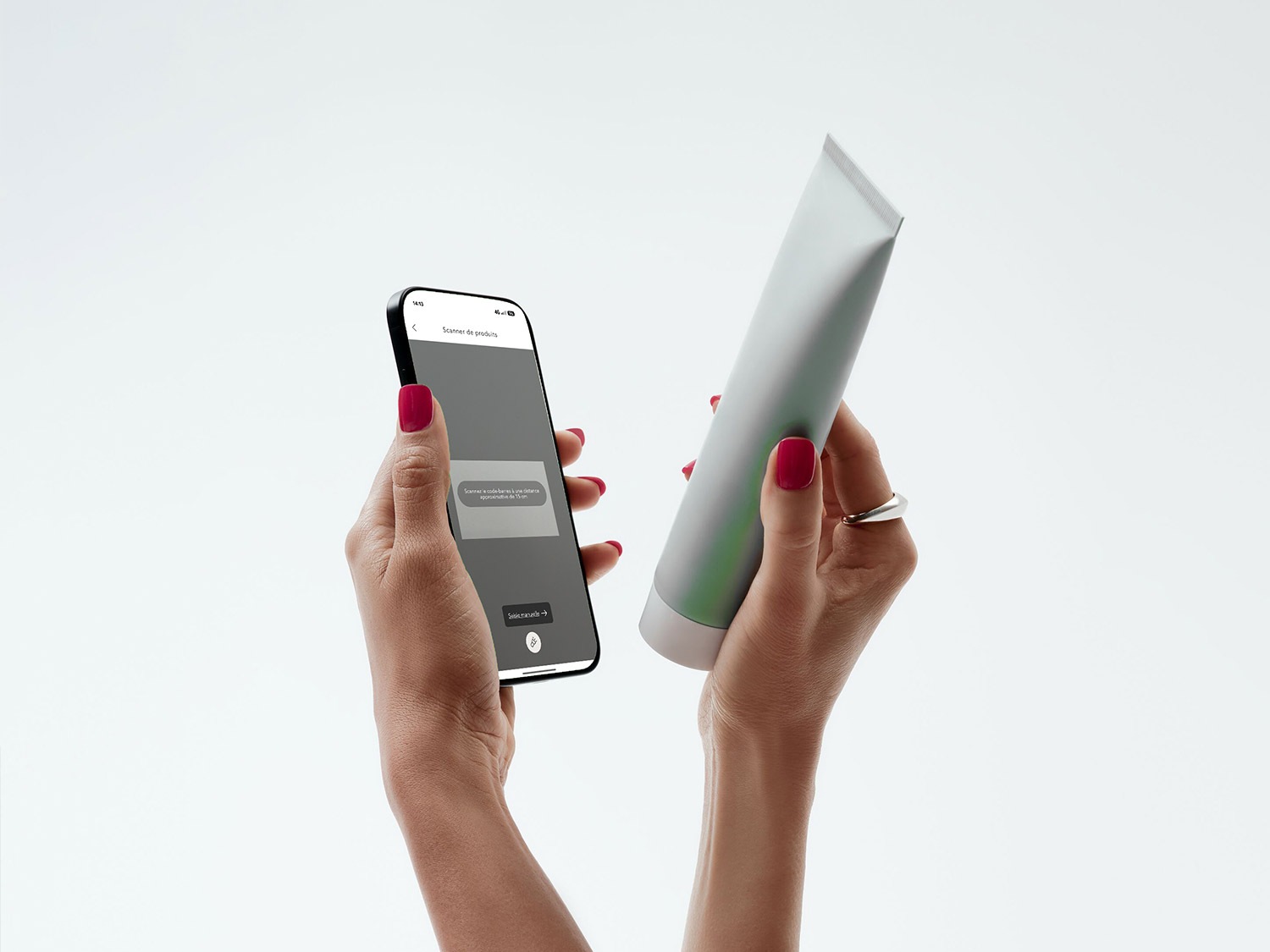 Une personne tient un tube gris argenté dans une main et un smartphone affichant un scanner de produits dans l'autre.