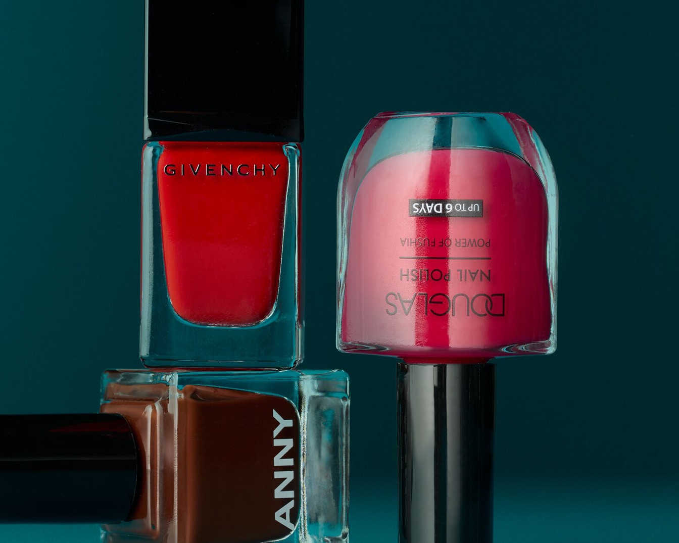 Verschiedene Nagellacke der Marken Givenchy in Rot, Anny in Braun und Douglas in Pink sind aufgereiht.
