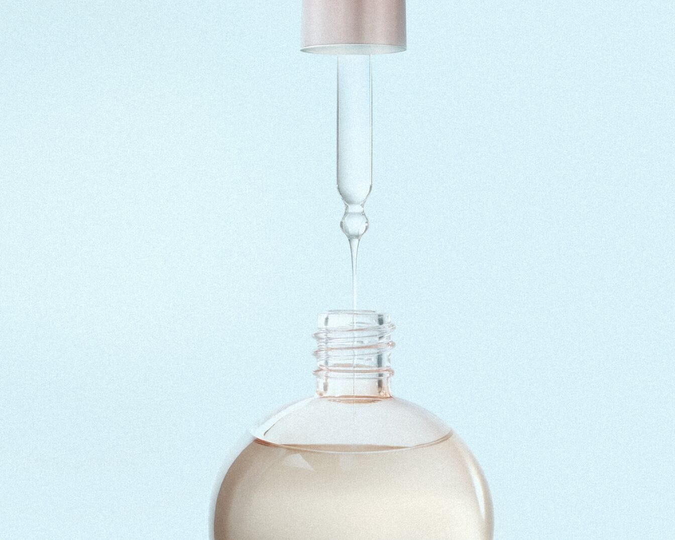 Sérum de beauté transparent versé à l'aide d'un compte-gouttes dans un flacon en verre sur fond bleu clair.
