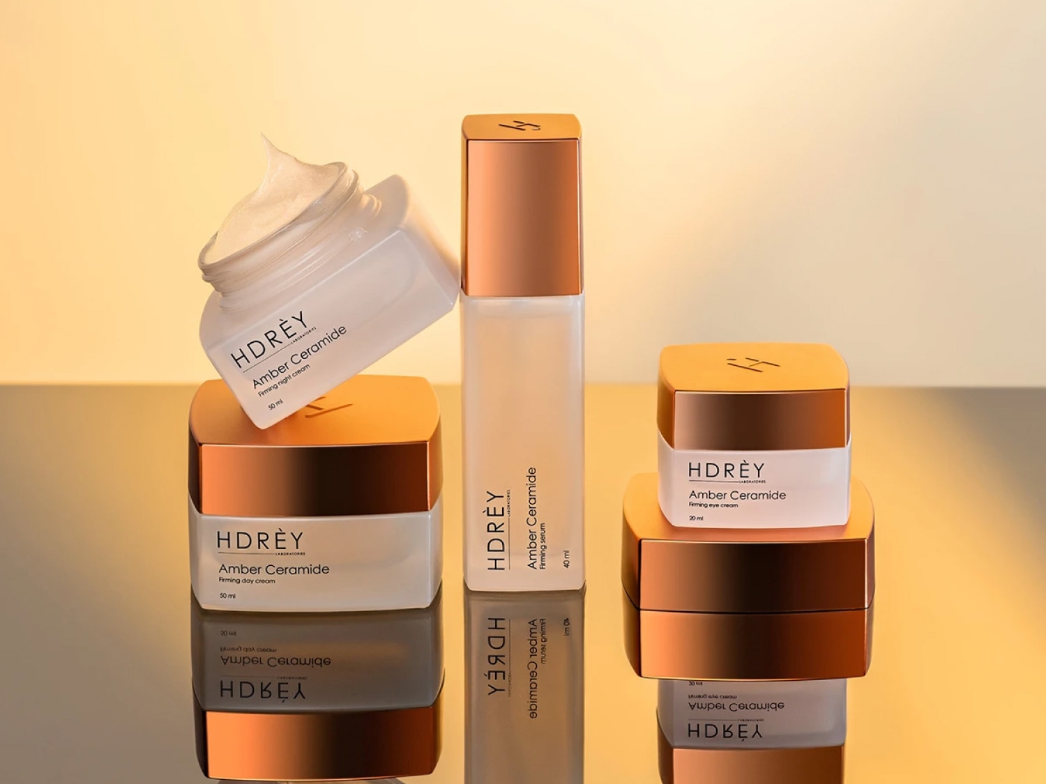 Kolekcja kosmetyków Hdrèy Amber Ceramide obejmuje krem na dzień, na noc, serum i krem pod oczy, wszystkie w eleganckich opakowaniach w odcieniach bieli i miedzi.