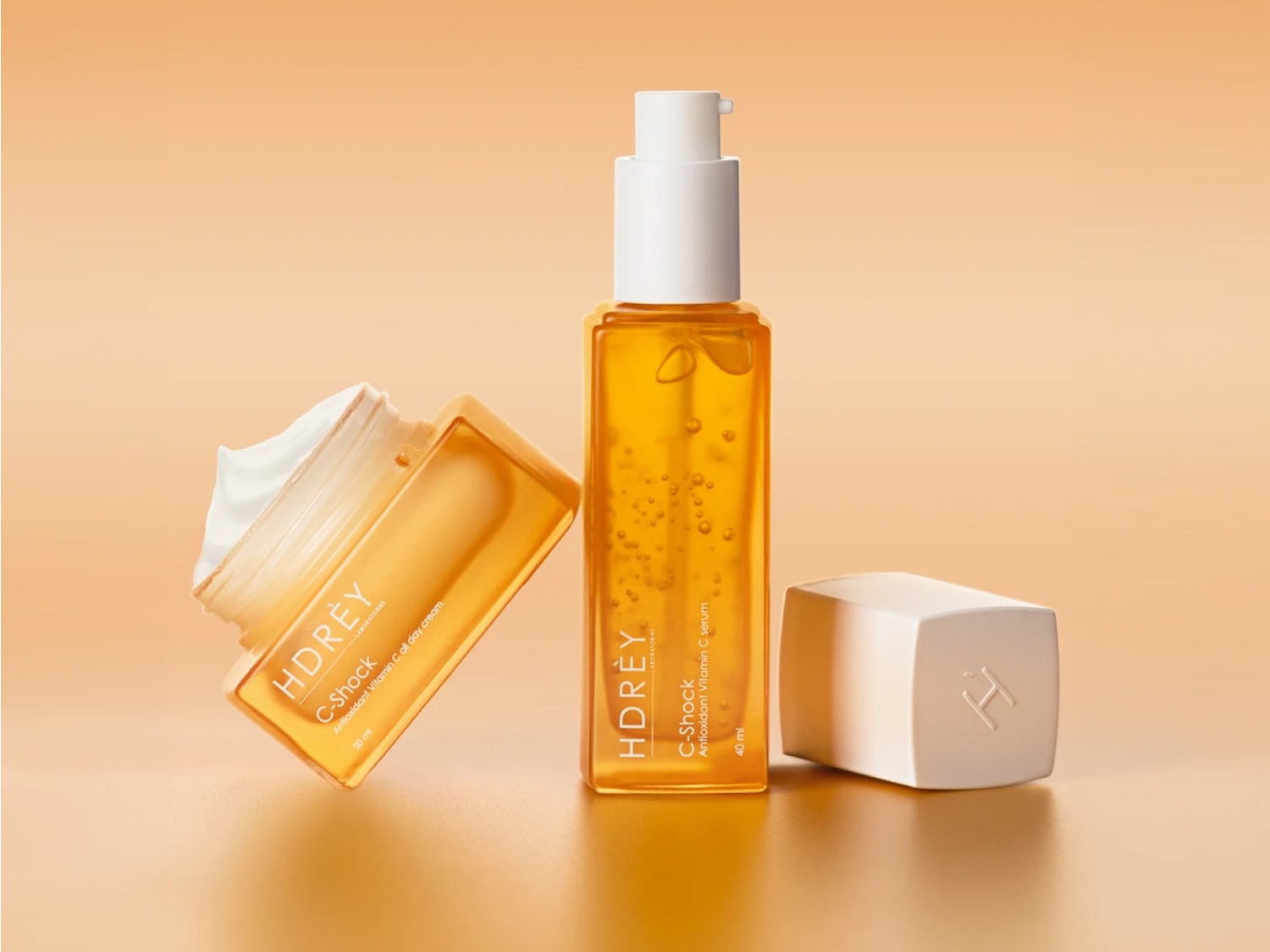 Żółty krem HDRÈY C-Shock Antioxidant Vitamin C all day cream w słoiczku o pojemności 50 ml oraz serum HDRÈY C-Shock Antioxidant Vitamin C serum w butelce z pompką o pojemności 40 ml.