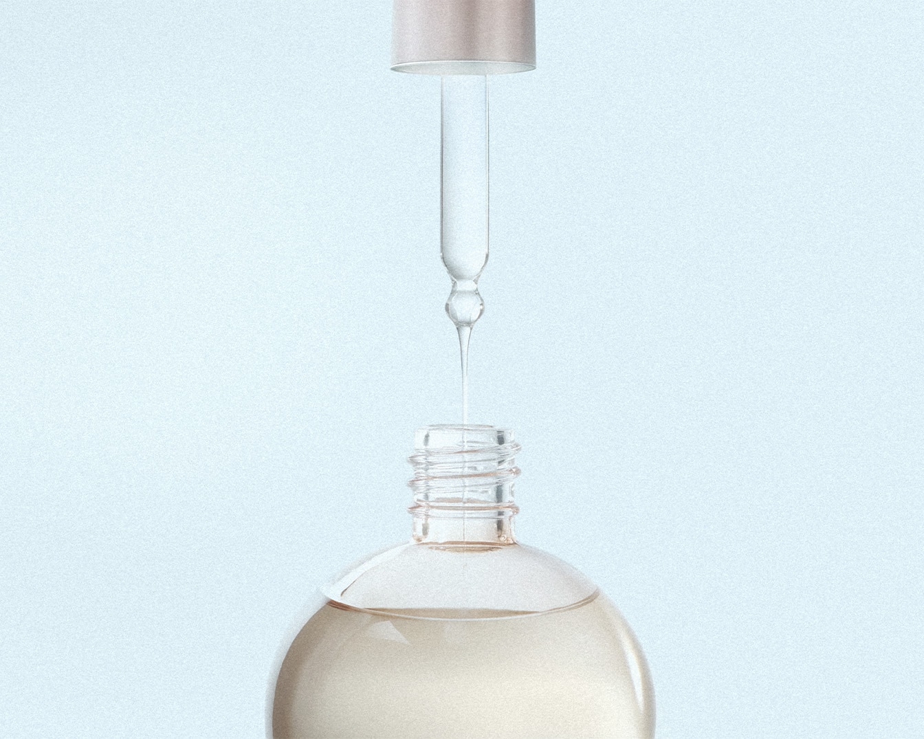 Un flacone di vetro trasparente contenente un liquido chiaro è aperto, con un contagocce che rilascia una goccia di siero, su uno sfondo azzurro.