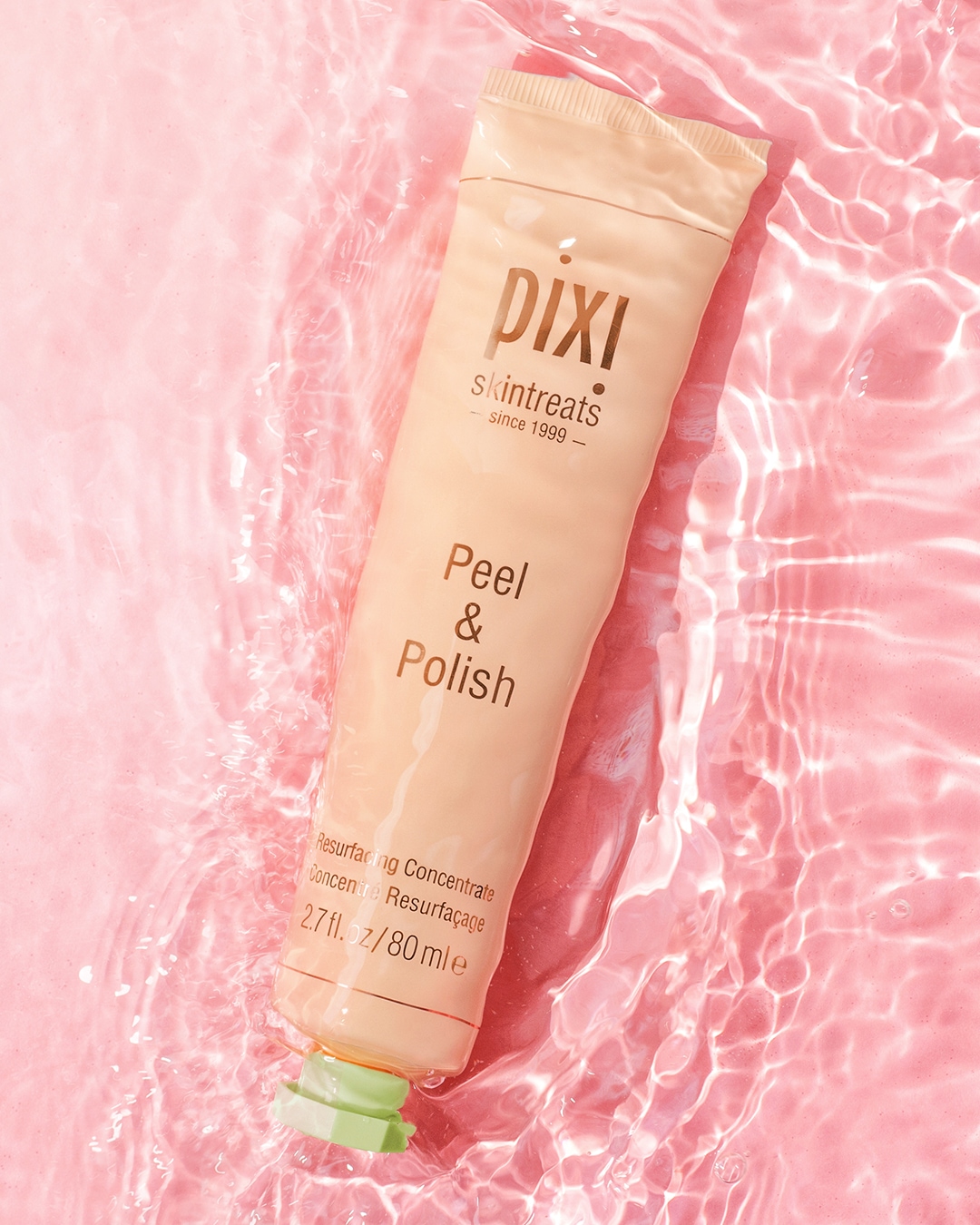 Jasnoróżowa tuba Pixi Skintreats Peel & Polish zanurzona w wodzie, obiecująca odnowę skóry dzięki resurfacing concentrate w pojemności 80 ml.