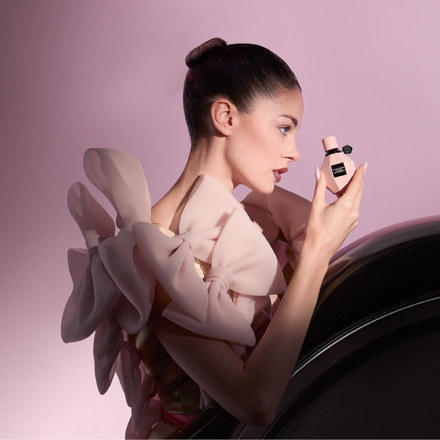 Un homme élégant en costume noir tient un flacon de parfum doré, accessoirisé d'un bracelet et d'un collier dorés, sur fond de table de jeu.