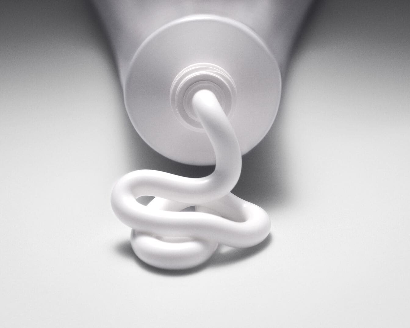 Nahaufnahme einer Tube mit weißer Creme, die in einer gewundenen Form herausgedrückt wird, ideal für Hautpflege oder medizinische Produkte.