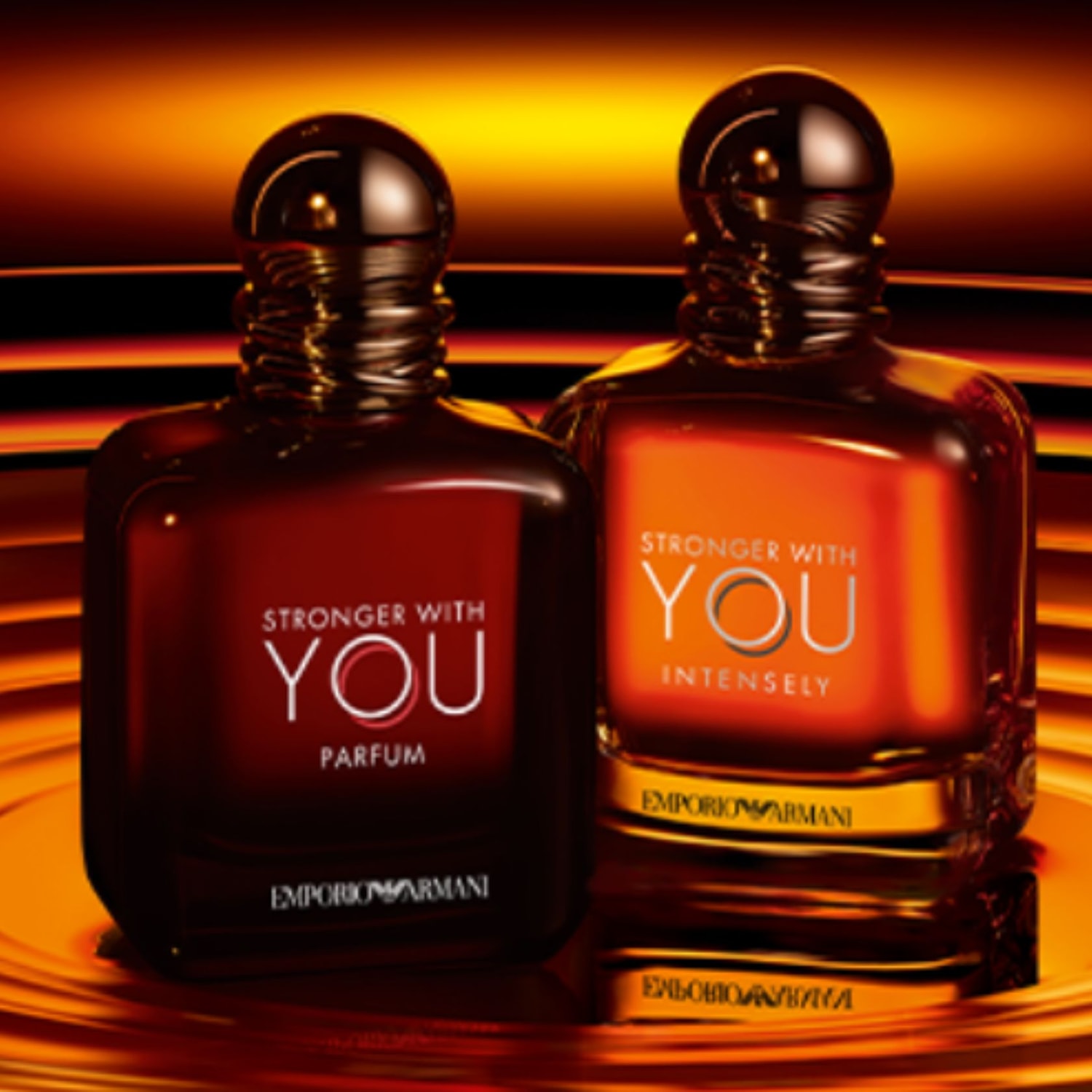 Két üveg Emporio Armani Stronger With You parfüm látható, az egyik mélyvörös, a másik narancssárga árnyalatú, elegáns és intenzív illatot sugallva.