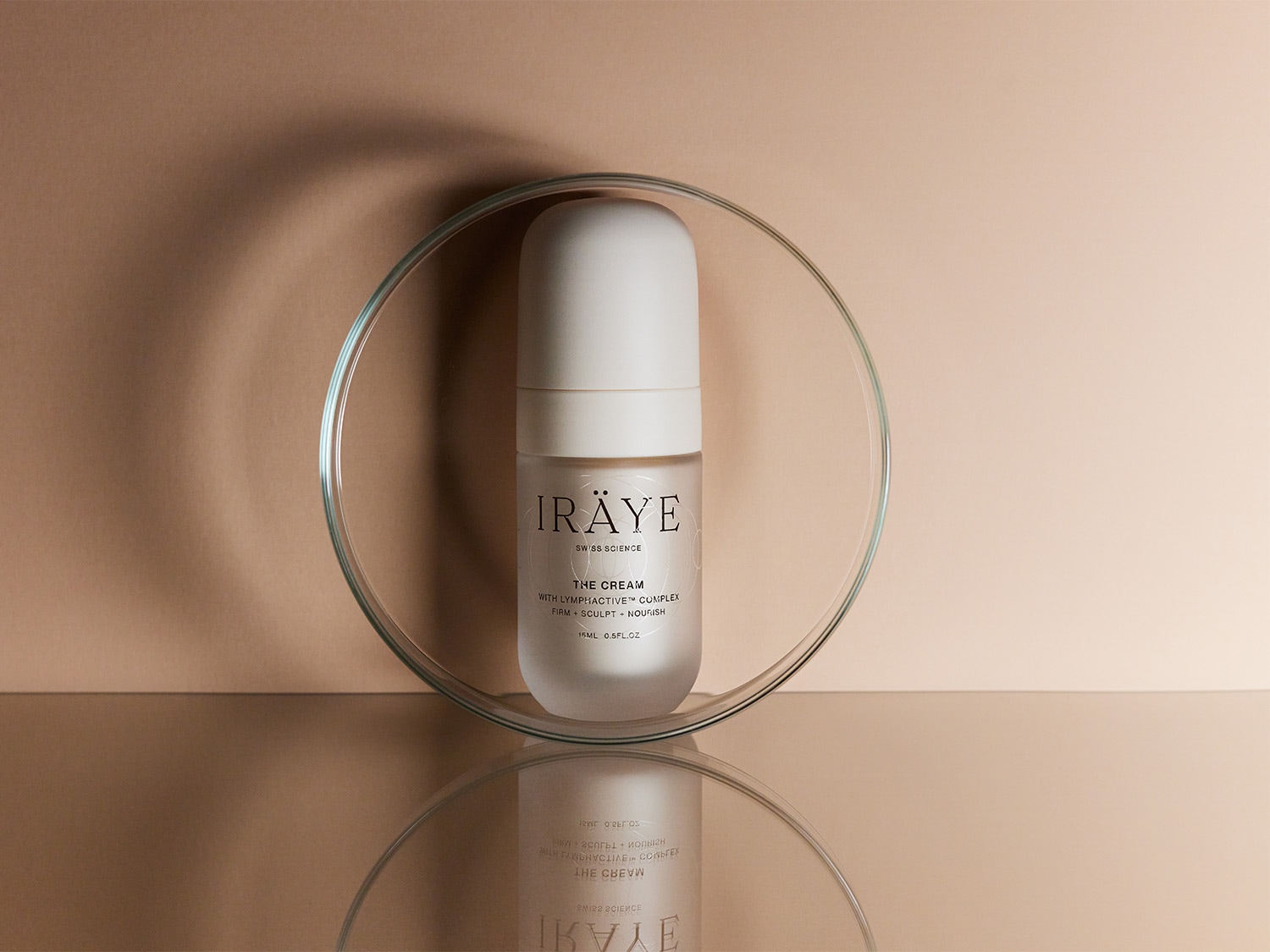 Eine Flasche der IRÄYE THE CREAM vor beigem Hintergrund.