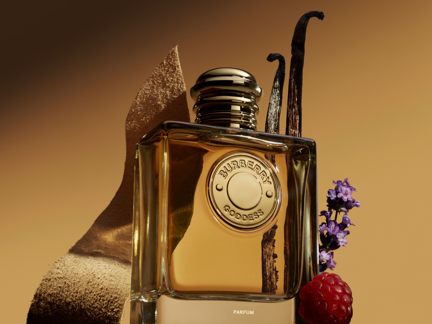 Butelka perfum Burberry Goddess o pojemności 100 ml ma złoty korek i jest otoczona kwiatami lawendy, laskami wanilii i zielonymi liśćmi.