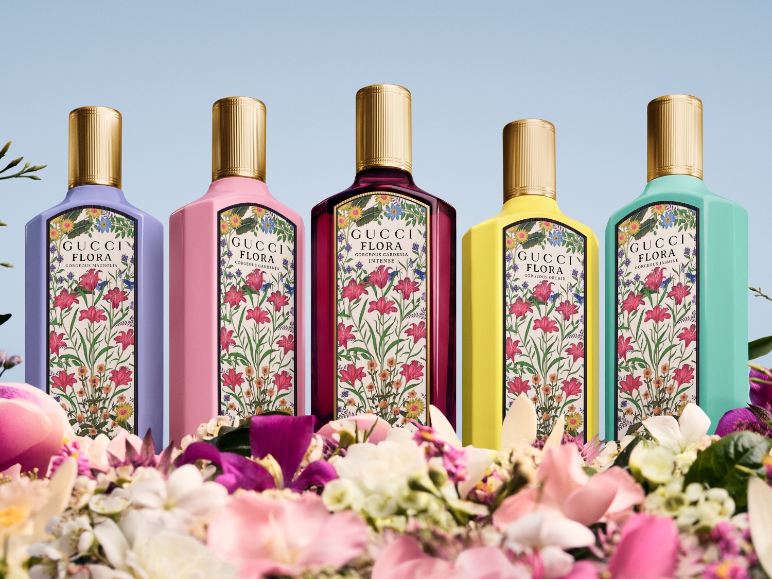 Cztery flakony perfum Gucci Flora w pastelowych kolorach: liliowym (Magnolia), różowym (Gardenia), żółtym (Orchid) i turkusowym (Jaśmin), każdy ozdobiony kwiatowym wzorem i złotym korkiem.