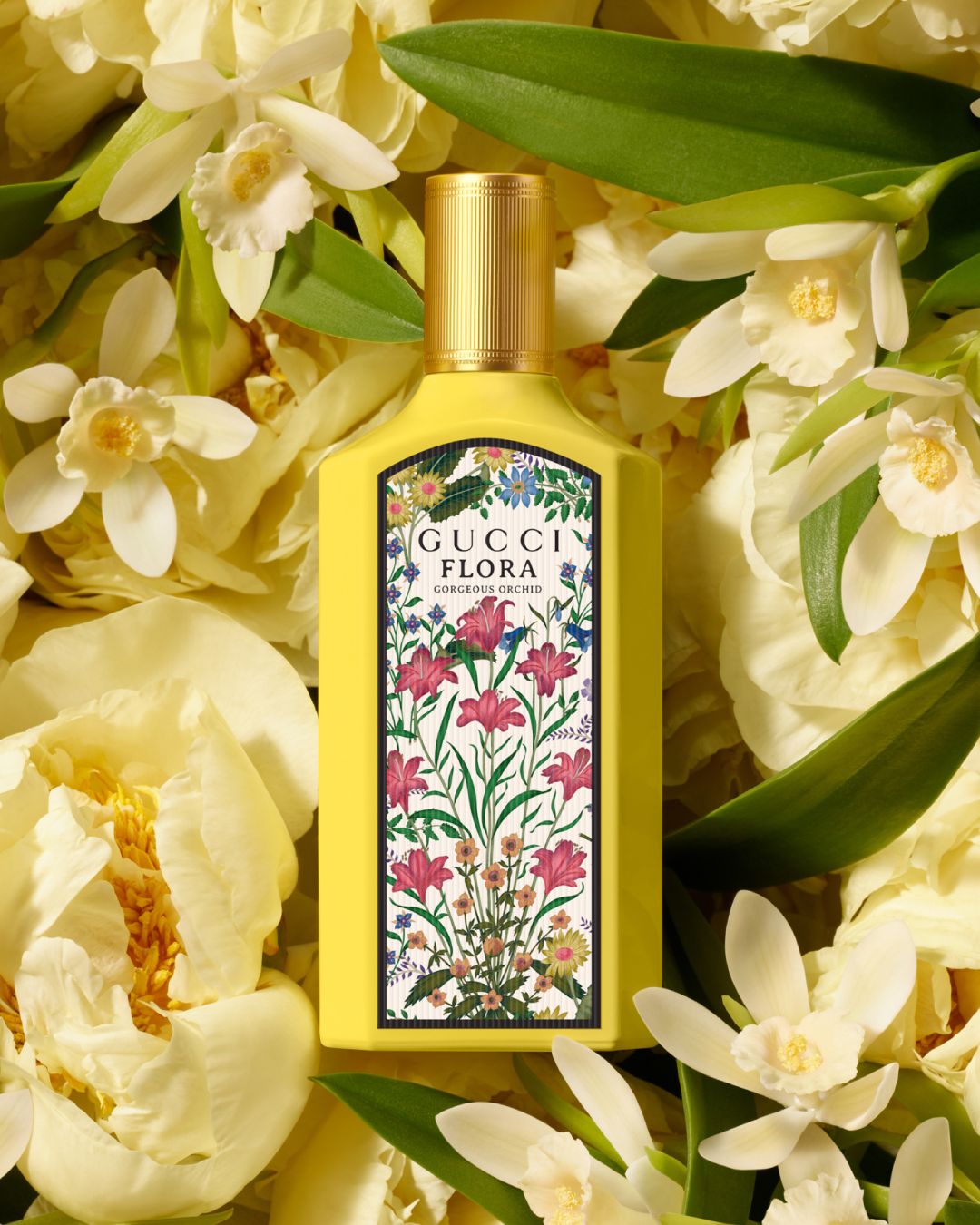 Żółty flakon perfum Gucci Flora Gorgeous Orchid otoczony białymi kwiatami, z etykietą ozdobioną kwiatowym wzorem.