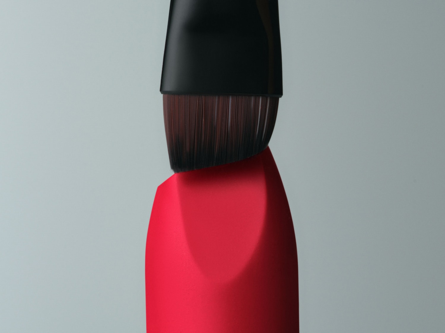 Gros plan d'un rouge à lèvres rouge vif avec un applicateur à pinceau noir, offrant une vue détaillée de la texture et de la couleur.