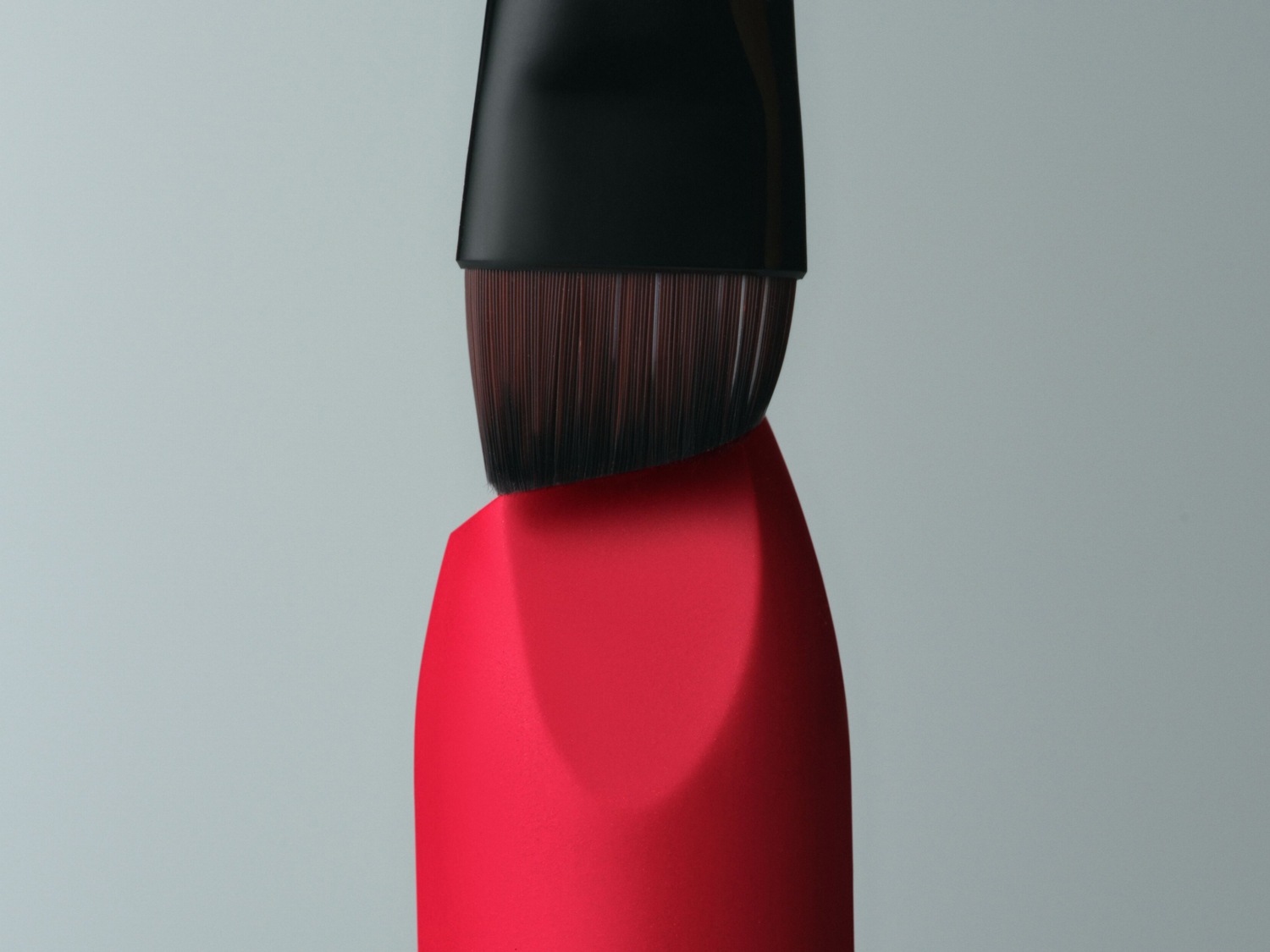 Gros plan d'un rouge à lèvres rouge vif avec un applicateur à pinceau noir, offrant une vue détaillée de la texture et de la couleur.