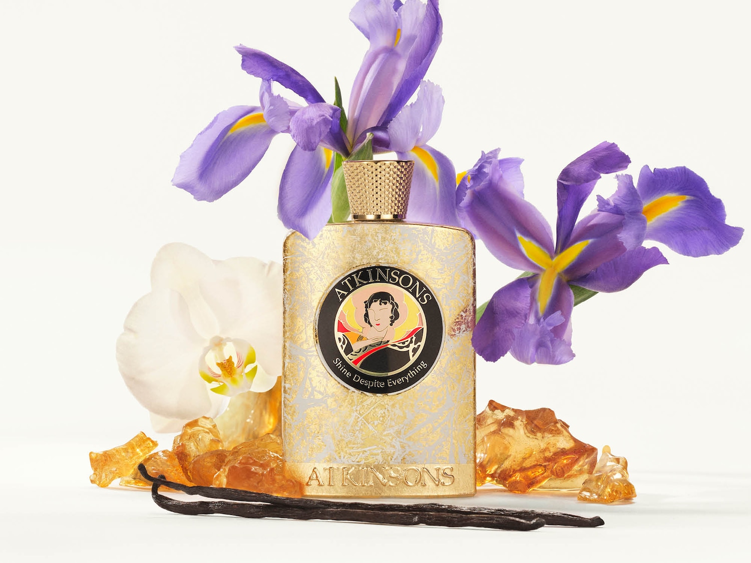 Atkinsons Duft präsentiert sich in einer goldenen Flasche mit floralen Akzenten und dem Slogan Shine Despite Everything.