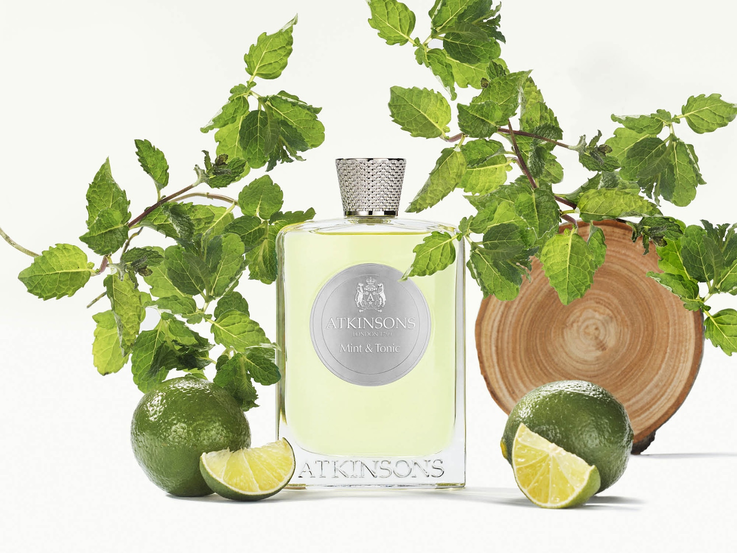 Erfrischendes Atkinsons Mint & Tonic Eau de Parfum, präsentiert in einem klaren Glasflakon mit silbernem Verschluss, umgeben von Limetten und Minze.