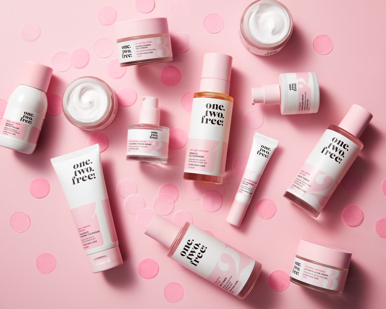 Ontdek de 'One. Two. Free!' huidverzorgingslijn met producten zoals gezichtsreinigers, serums en crèmes in roze en witte verpakkingen.