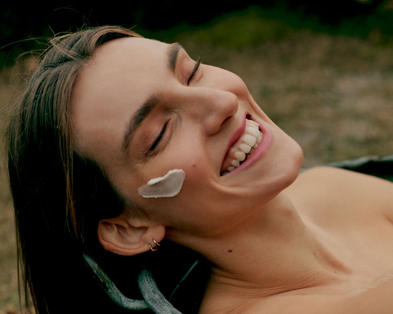 Egy mosolygó nő arca, a bőrén krémmel, a szeme csukva, a bőre sima és hidratáltnak tűnik.