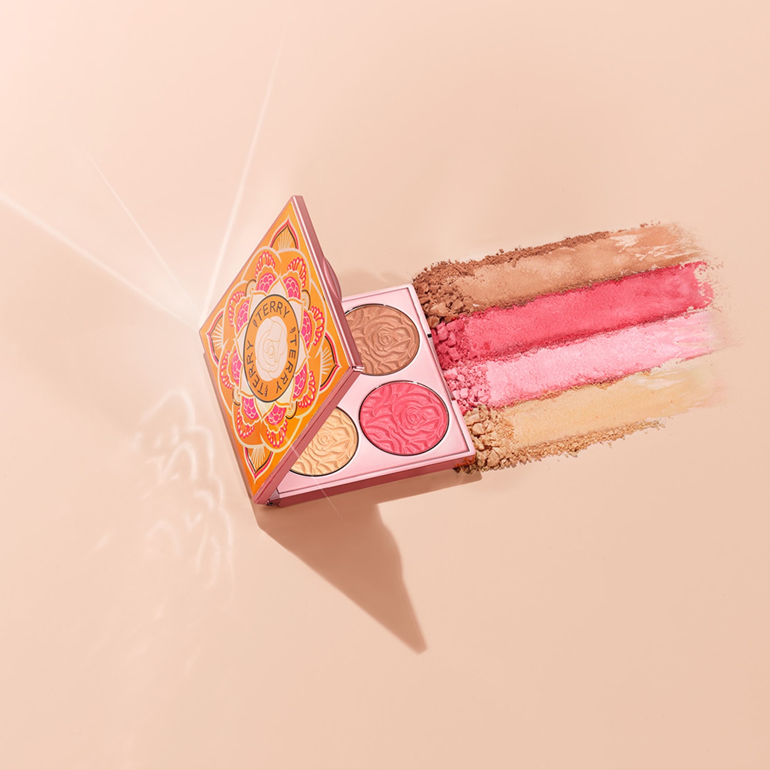 Paleta do makijażu By Terry z czterema odcieniami różu i bronzera, z których każdy ma wytłoczony wzór róży, a obok niej rozmazane paski pudru.