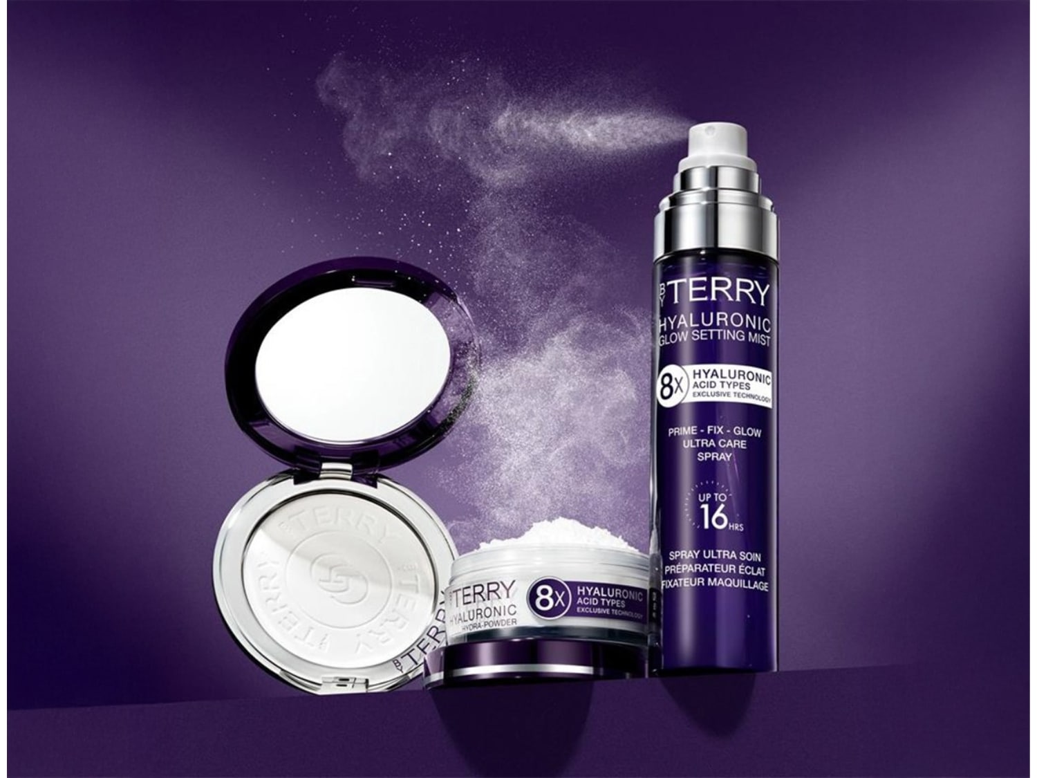 Na fioletowym tle puder i mgiełka By Terry Hyaluronic Glow Setting Mist, które zapewniają efekt promiennej skóry i utrwalają makijaż do 16 godzin.