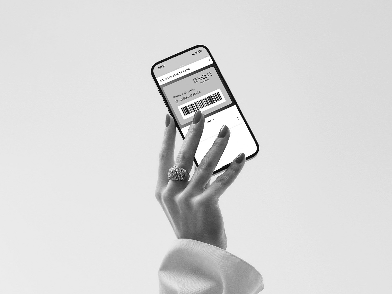 Eine Person öffnet eine hellgraue Geschenkbox, die mit einem passenden Band und einer Schleife verziert ist, während sie elegante Ringe trägt.