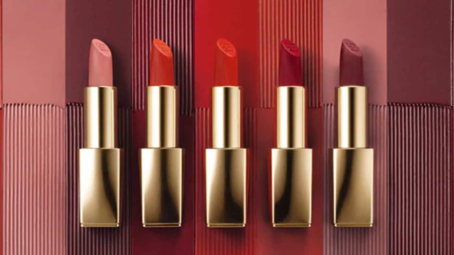 Fünf Lippenstifte in verschiedenen Rottönen mit goldener Hülse, die ein Spektrum von sanftem Rosa bis tiefem Burgunderrot zeigen.