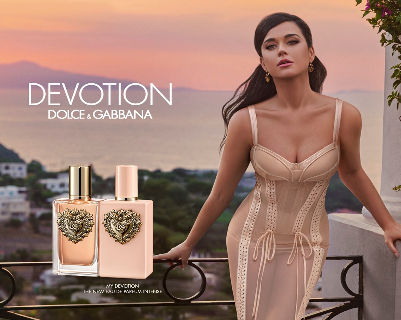 De nieuwe Eau de Parfum Intense van Dolce & Gabbana, MY DEVOTION, gepresenteerd met twee flessen in zachte kleuren en een elegante vrouw op de achtergrond.