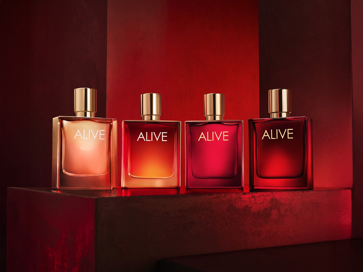 Découvrez la collection de parfums ALIVE, chacun dans un flacon carré aux nuances de rouge, coiffé d'un bouchon doré.