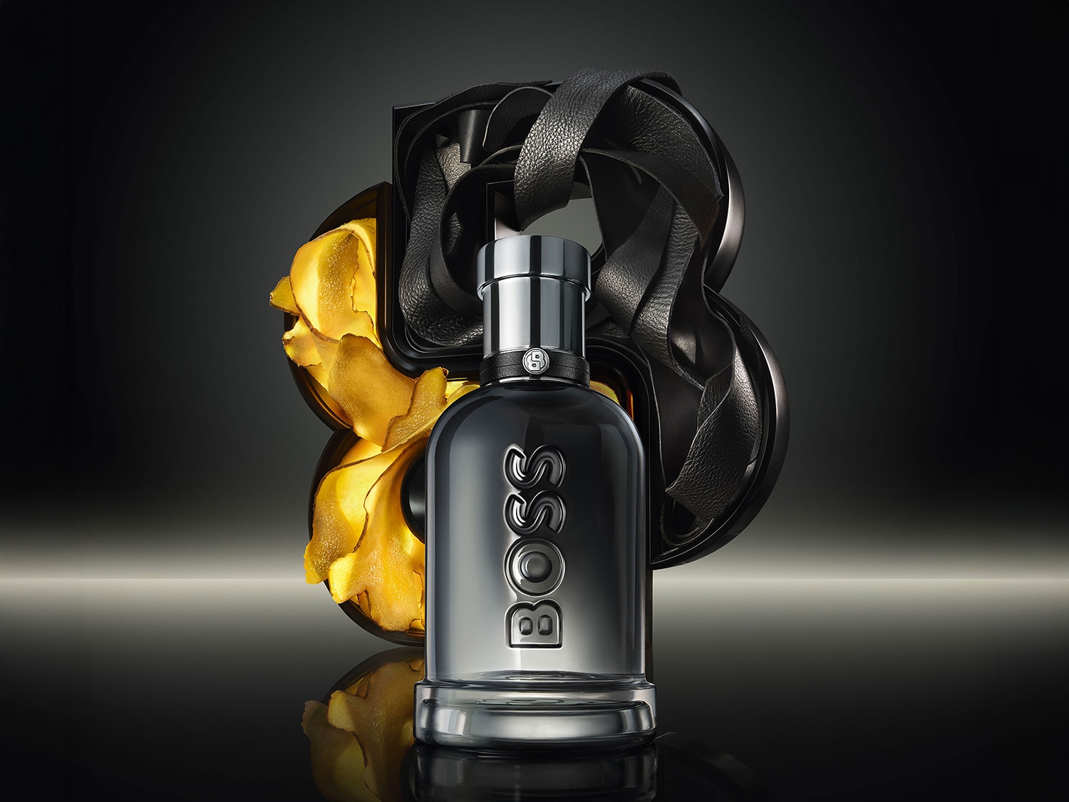 Découvrez le parfum BOSS The Scent, un parfum élégant dans un flacon gris argenté, orné du logo BOSS en relief, avec des accents dorés et noirs.