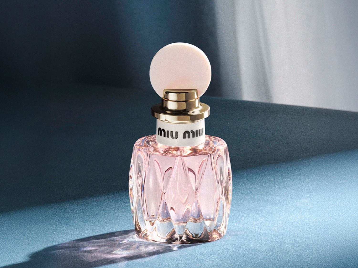 Découvrez le parfum Miu Miu, présenté dans un flacon en verre rose délicat avec un bouchon rond et clair, parfait pour ajouter une touche de féminité à votre quotidien.