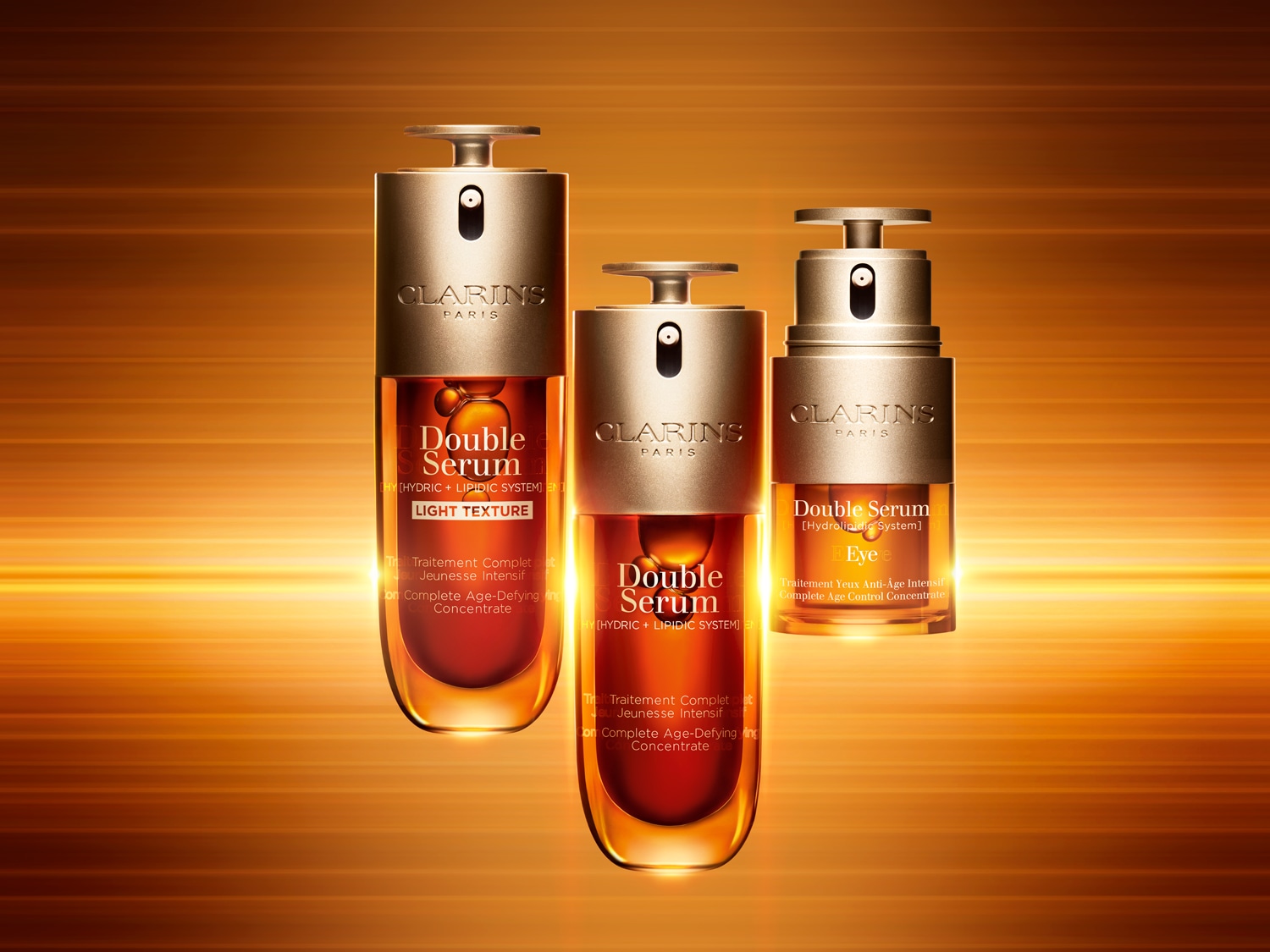 Drie flessen Clarins Double Serum, waarvan één Light Texture en één voor de ogen, staan op een goudkleurige achtergrond.