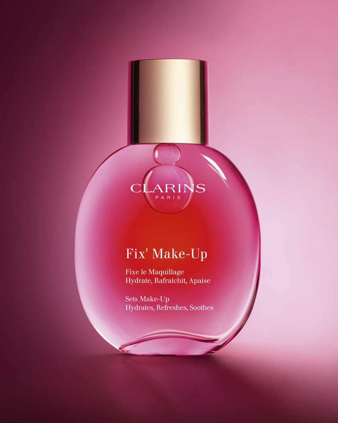 Een roze Clarins Fix' Make-Up fles met een gouden dop die de make-up fixeert, hydrateert, verfrist en verzacht.