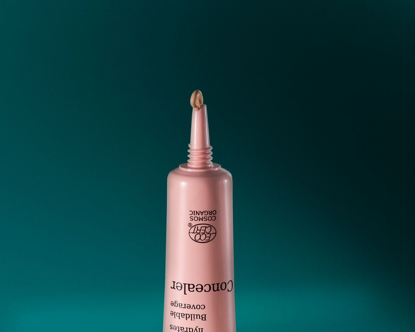 Roze concealer tube met een druppel product op de applicator, ideaal voor een buildable dekking.