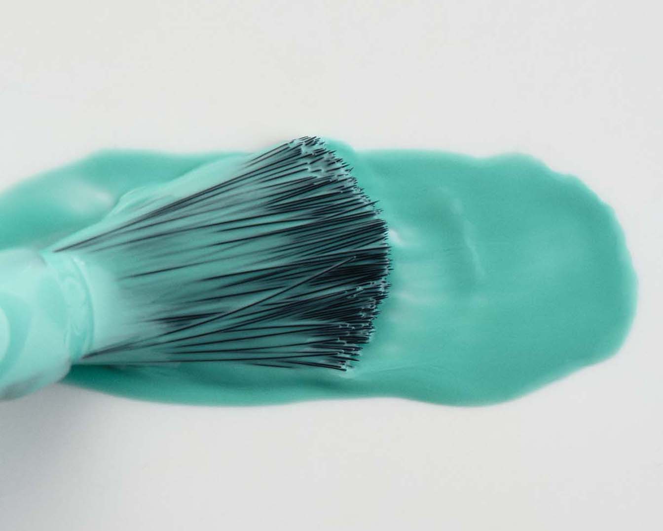 Nahaufnahme eines Pinselapplikators mit türkisfarbener Flüssigkeit, die eine glatte, glänzende Textur zeigt.