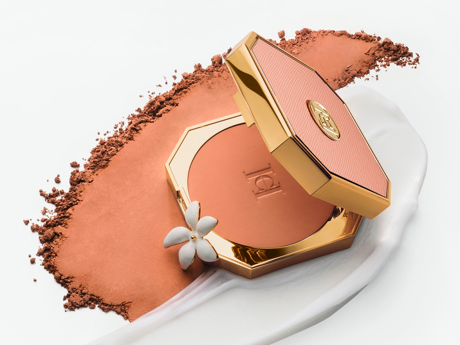 Das offene, goldumrandete Carolina Herrera Rouge liegt auf einem Klecks weißer Creme und losem, passendem Rougepuder.