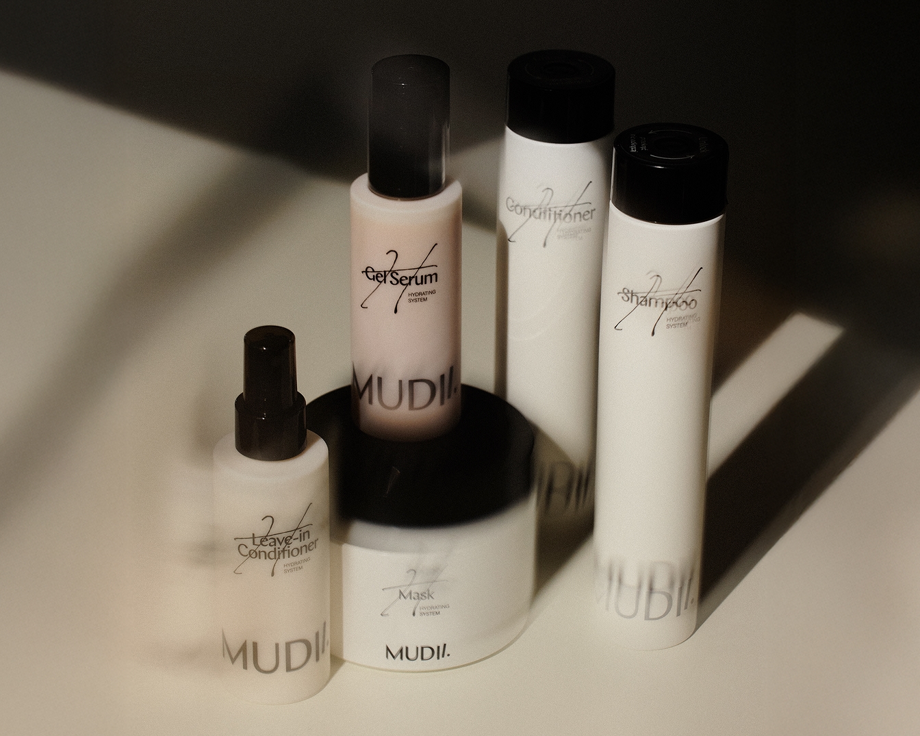 Zestaw produktów do pielęgnacji włosów MUDII, w skład którego wchodzą szampon, odżywka, serum w żelu, maska i odżywka bez spłukiwania, zapewniające kompleksową pielęgnację i nawilżenie.