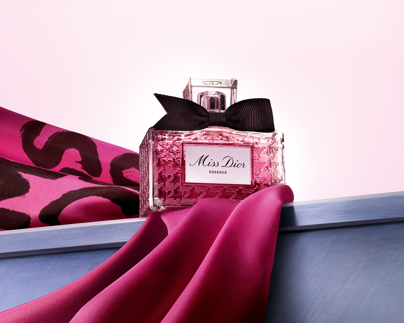 Découvrez Miss Dior Essence, un parfum floral et délicat présenté dans un flacon orné d'un nœud noir, évoquant l'élégance et le raffinement.