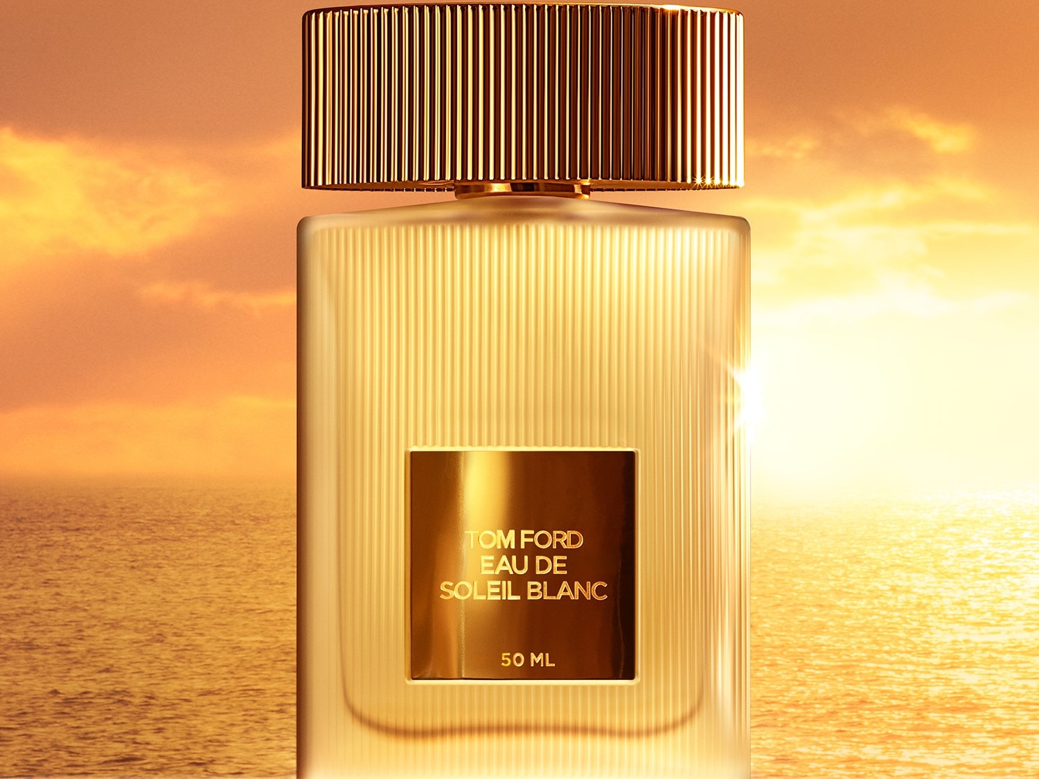 Butelka perfum Tom Ford Eau de Soleil Blanc o pojemności 50 ml, z przezroczystego szkła ze złotą etykietą, na tle morza o zachodzie słońca.