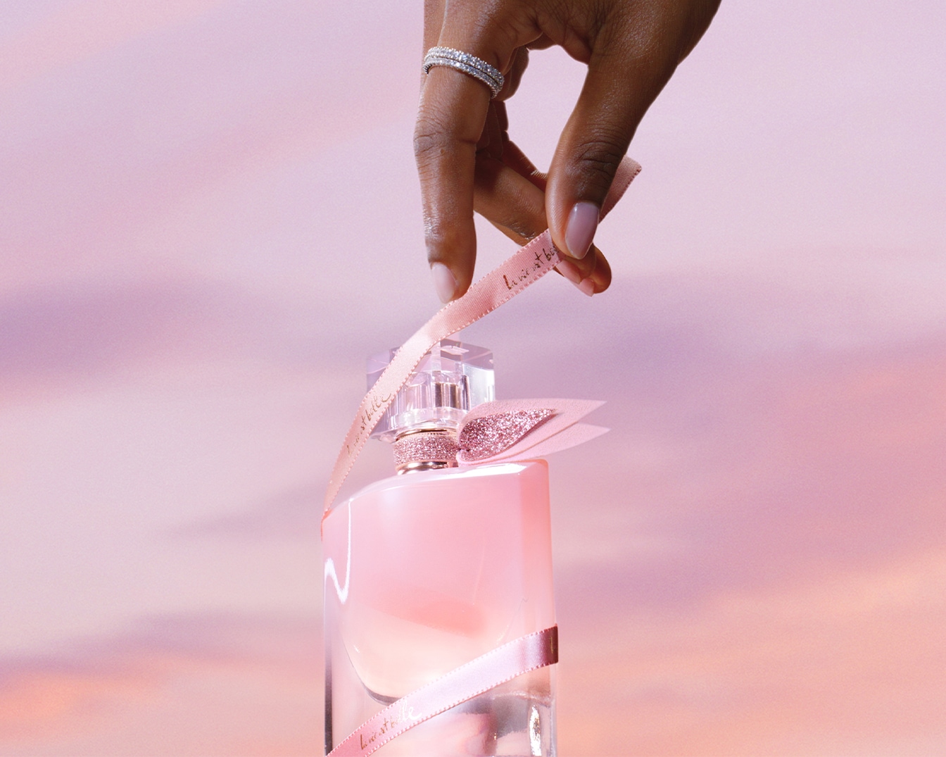 Découvrez le parfum La Vie est Belle dans son flacon rose, orné d'un ruban délicat, symbole d'élégance et de féminité.