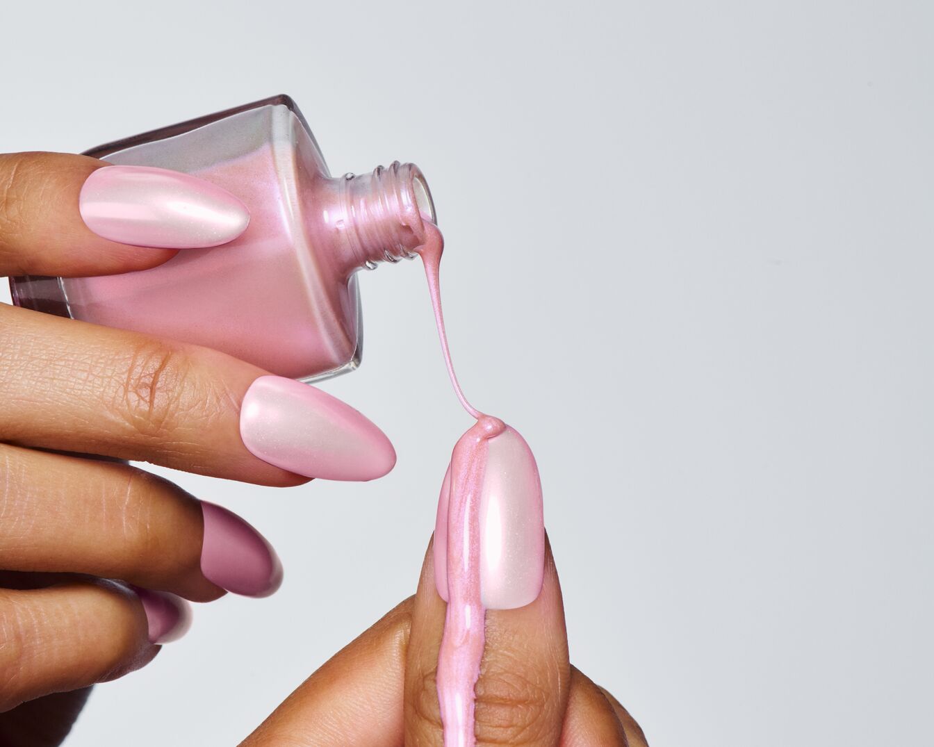 Ein glänzender, rosa Nagellack wird auf einen Fingernagel aufgetragen, um eine schimmernde Maniküre zu erzielen.