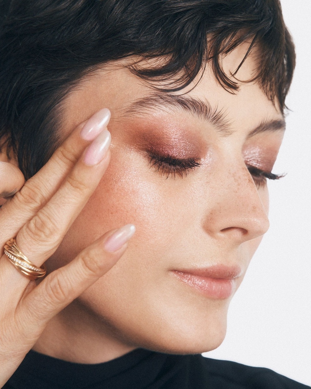 A nő közeli portréja, rózsaszín szemhéjfestékkel, arany gyűrűvel és fényes körmökkel, a tökéletes smink megjelenésért.