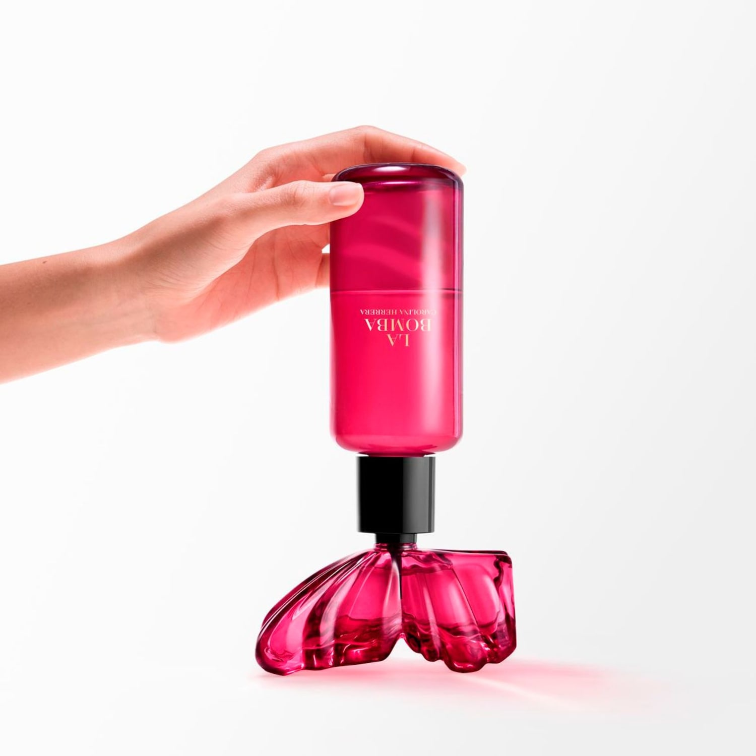 Detailní pohled na parfém Carolina Herrera La Bomba v růžovém flakonu s originálním designem, držený v ruce.