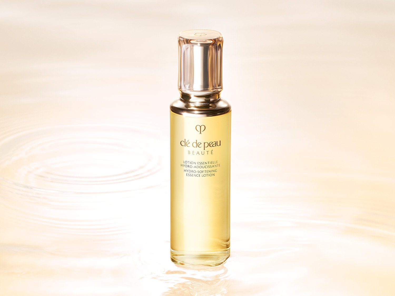 Die Clé de Peau Beauté Lotion Essentielle Hydro-Adoucissante ist eine aufhellende Essenzlotion in einer durchsichtigen Glasflasche mit goldenem Verschluss.