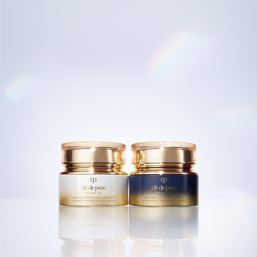 Zwei Tiegel von Clé de Peau Beauté, die Tages- und Nachtcreme mit goldfarbenen Deckeln, versprechen fortschrittlichen Schutz und intensive Pflege.