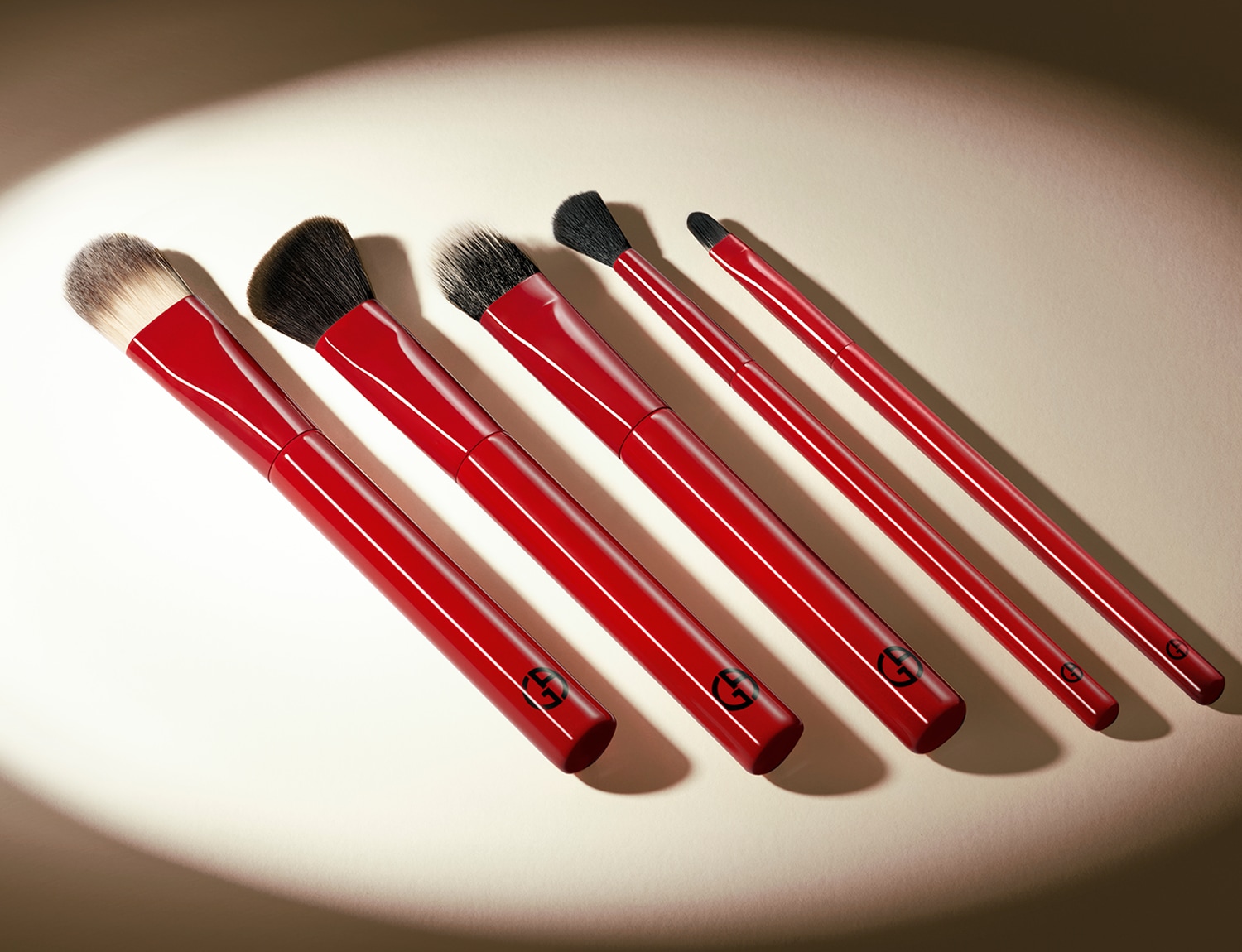 Sada pěti štětců na make-up Giorgio Armani s červenými držadly a různými velikostmi štětin pro dokonalý vzhled.