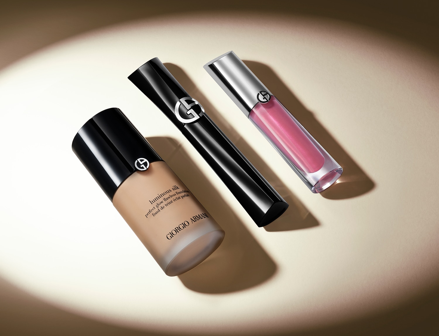 Trio kosmetiky Giorgio Armani: béžový make-up Luminous Silk, černá řasenka a růžový lesk na rty s lesklým stříbrným víčkem.