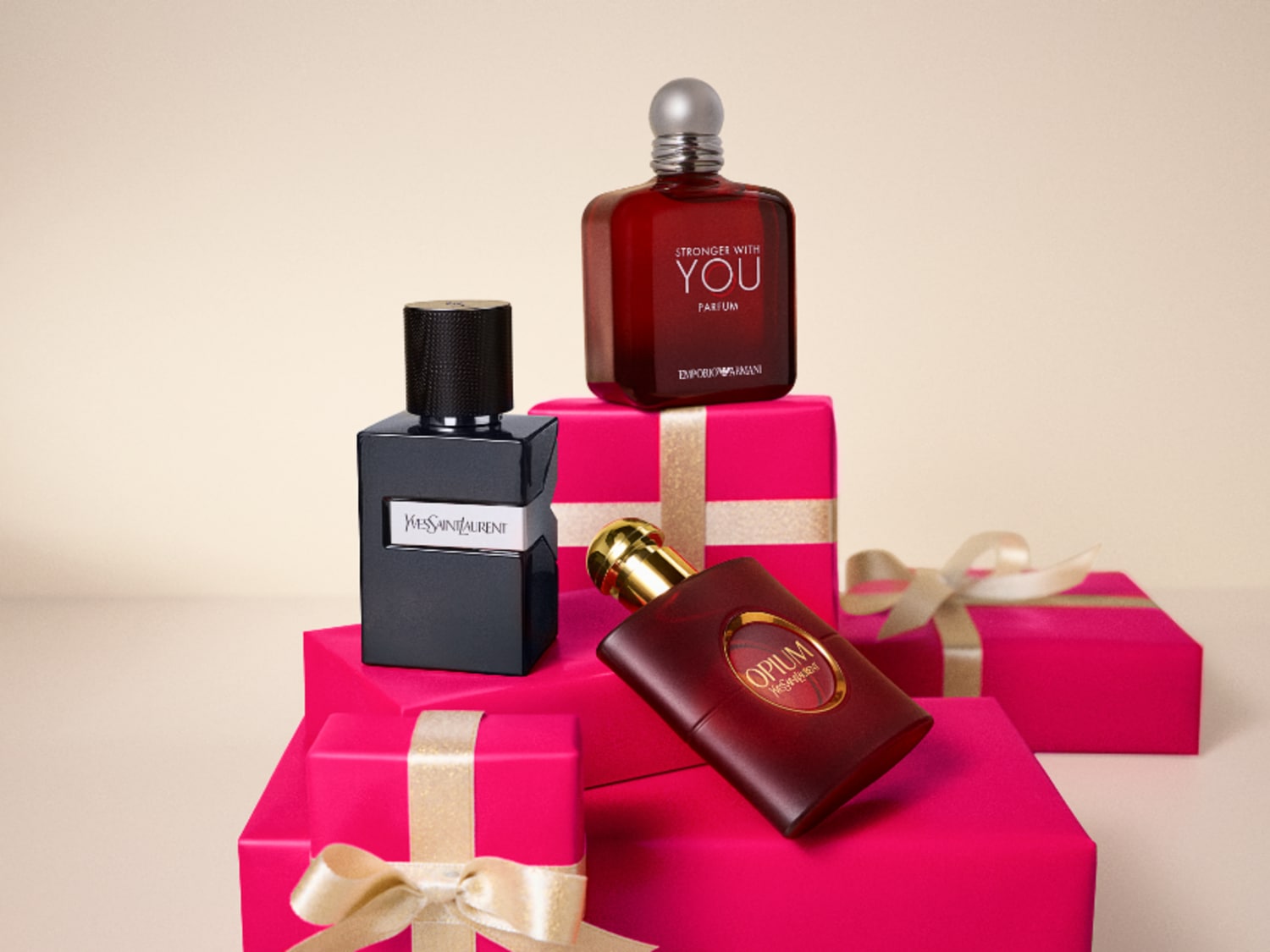 Découvrez un assortiment de parfums de marques de luxe comme Yves Saint Laurent et Emporio Armani, présentés sur des boîtes cadeaux roses.